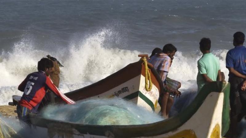 Fishermen near their boats as waves break on the cost of the Bay of Bengal in Chennai on Thursday. (Photo: PTI)