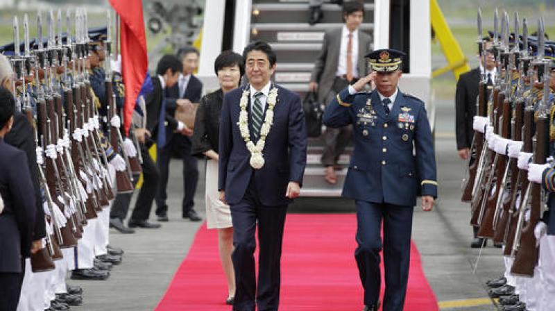 Japanese Prime Minister Shinzo Abe, followed by his wife Akie, walks during arrival honors at Manilas airport, Philippines. (Photo: AP)