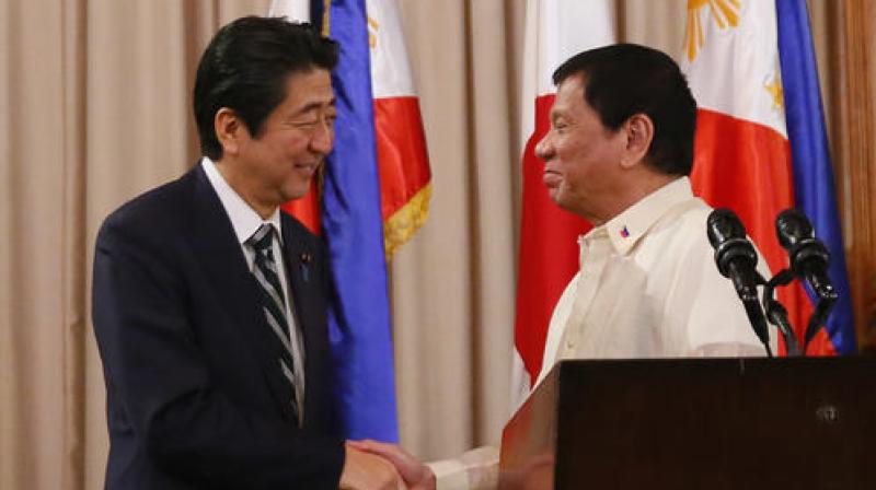 Japanese Prime Minister Shinzo Abe, shakes hands with Philippine President Rodrigo Duterte, following their joint statement at the Malacanang Palace in Manila. (Photo: AP)