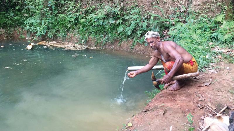 Water oozes out of suranga (tunnel in the back) through a pipe and being collected in an open pond at Bedadka in Kasargod.