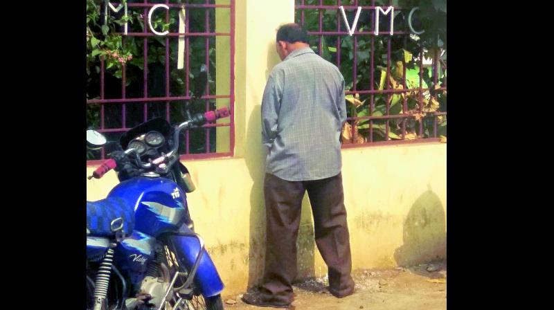 A man urinates on the VMC office wall in Vijayawada though the VMC has installed Mana toilets at many places in the city. (Photo: DECCAN CHRONICLE)