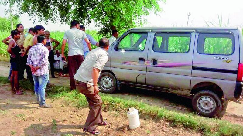 Villagers look on as police investigates near the vehicle, Maruti Suzuki Eeco, which was attacked by criminals on Jewar-Bulandshahr road off Yamuna Expressway in Gautam Budh Nagar district early Thursday morning. The armed criminals reportedly robbed them, killed the driver, and allegedly raped the woman members. (Photo: PTI)