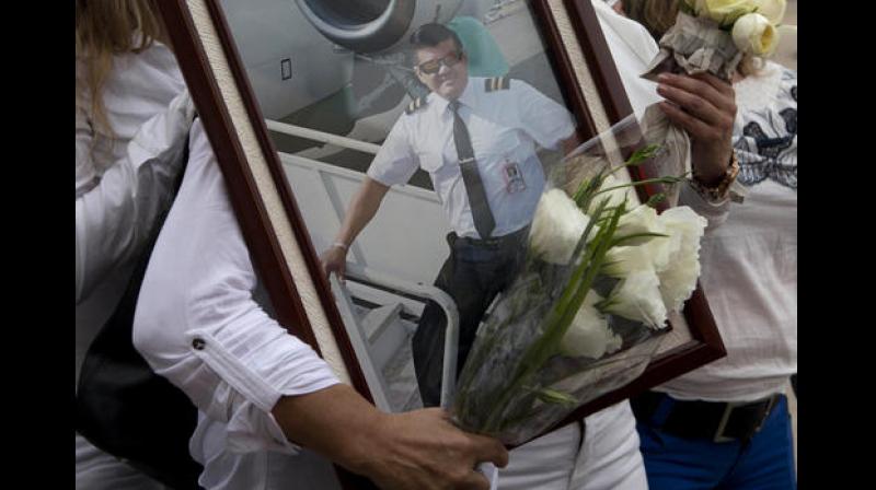 A relative of LaMia pilot Marcelo Quiroga, who died in a plane crash in Colombia, holds his pictures as his remains arrive at the Viru Viru airport in Santa Cruz, Bolivia. (Photo: AP)