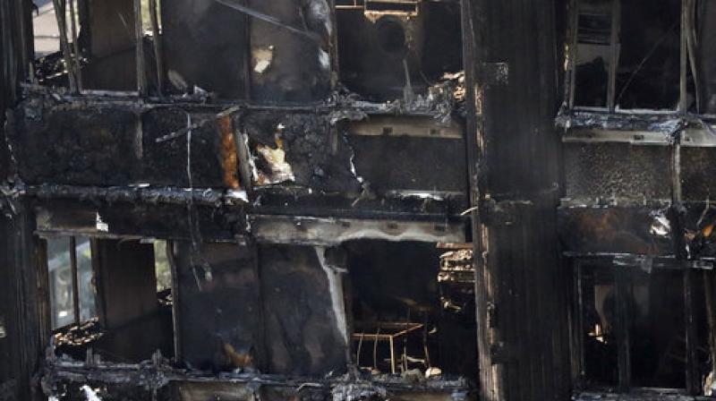 Remains of furniture are seen through the windows as smoke still emerges from the charred Grenfell Tower in London. (Photo: AP)