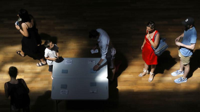 Voters pick up ballots before voting for the second round of parliamentary elections, in Lyon, central France. (Photo: AP)