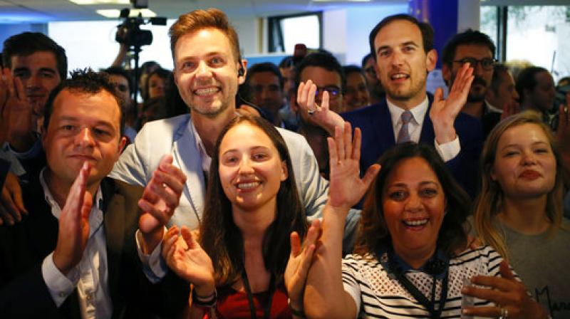 La Republique en Marche party members react after the announcement of the partial official results and polling agencies projections in the final round of parliamentary elections are announced at the party headquarters, in Paris, France. (Photo: AP)