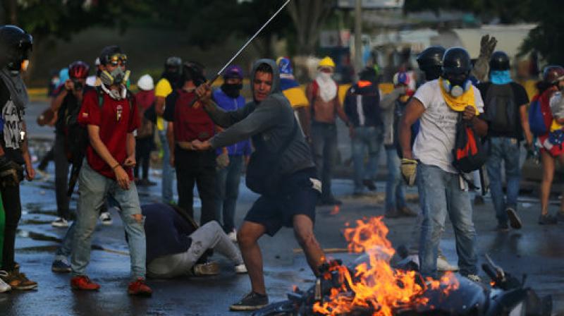 An anti-government demonstrator uses a golf club to hit a burning motorcycle protesters took away from National Guards who blocked them from marching to the office of Attorney General Luisa Ortega Diaz, to show support for the one-time government loyalist, in Caracas, Venezuela. (Photo: AP)
