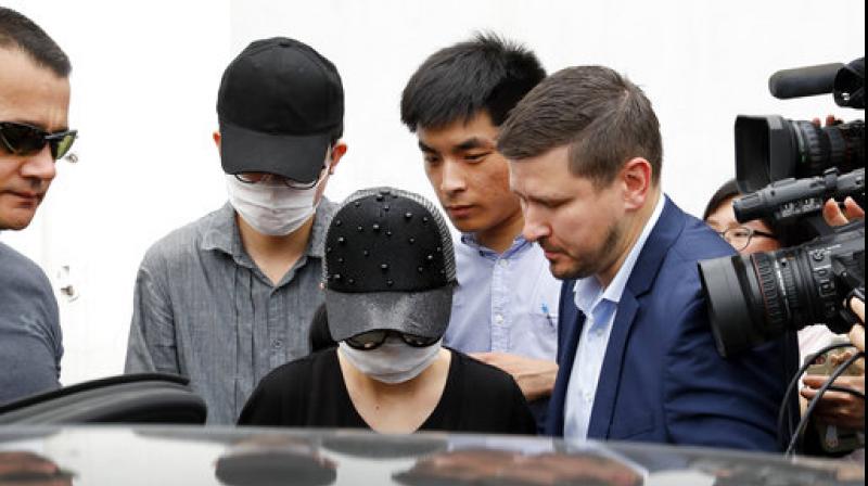 Unidentified Crown Resorts employees wearing face masks are escorted by securities as they leave the Baoshan District Peoples Court after attending her trial in Shanghai, China. (Photo: AP)