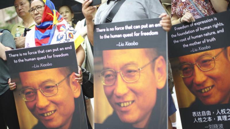 Participants, one wearing a Tibetan flag, hold photos of Liu Xiaobo during a vigil honoring Xiaobos legacy and to protest continued human rights abuses in China. (Photo: AP)