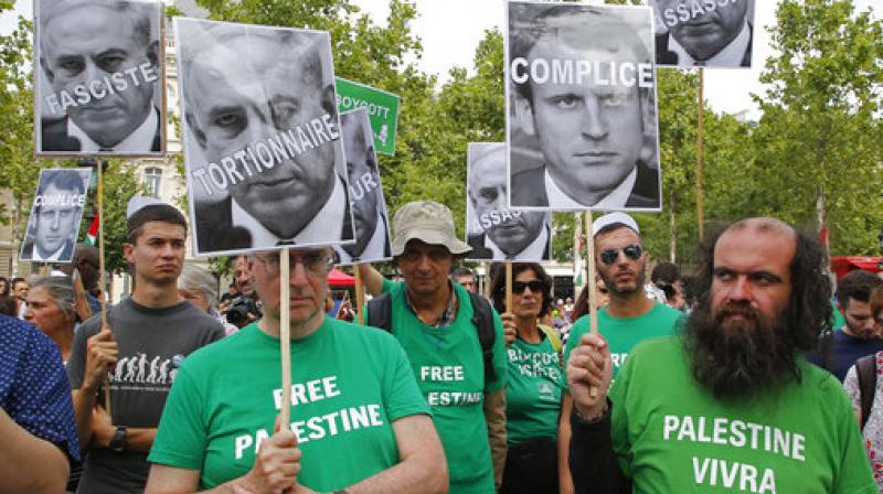 Pro-Palestinian activists hold pictures of Israeli Prime Minister Benjamin Netanyahu and French President Emmanuel Macron as they gather to protest Israeli Prime Ministers visit to France in Paris. (Photo: AP)