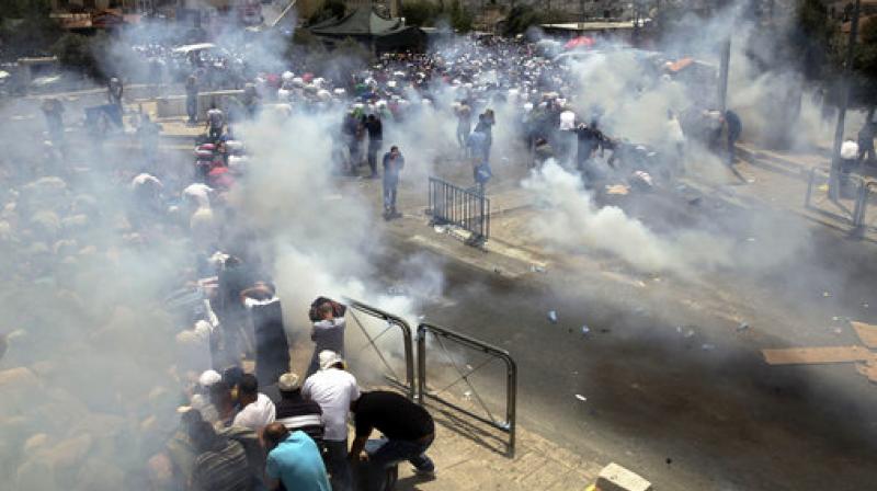 Palestinians run away from tear gas fired by Israeli forces in Jerusalem. An escalating dispute over metal detectors at a contested Jerusalem shrine turned violent on Friday, setting off widespread clashes between Palestinian stone-throwers and Israeli troops. (Photo: AP)