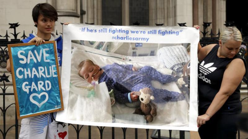 Supporters of critically ill baby Charlie Gard hold up a photograph of him after his court case finished for the day at the High Court in London. The parents of the 11-month old, who has a rare genetic condition and brain damage, returned to court Friday hoping for a fresh analysis of their wish to take the critically ill child to the United States for medical treatment. (Photo: AP)
