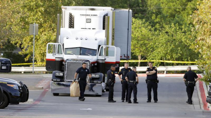 San Antonio police officers investigate the scene Sunday where eight people were found dead in a tractor-trailer loaded with at least 30 others outside a Walmart store in stifling summer heat in what police are calling a horrific human trafficking case, in San Antonio.