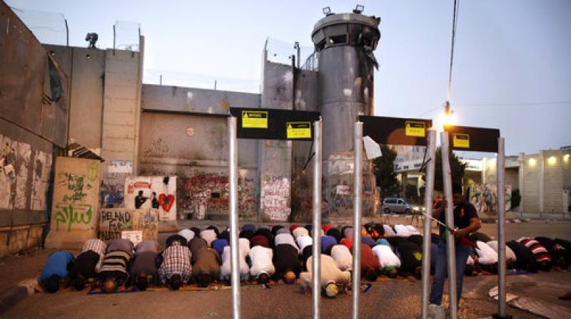 Palestinians pray in front of mock metal detectors during a demonstration in Bethlehem.  Israels minister of public security said Sunday that metal detectors set at the entrance to a major Jerusalem shrine that angered Palestinians could be removed if police have another way of ensuring security there. (Photo: AP)