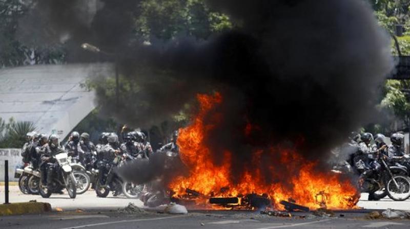 Venezuelan Bolivarian National police officers drive around fire after an explosion at Altamira square during clashes against anti-government demonstrators in Caracas, Venezuela. (Photo: AP)