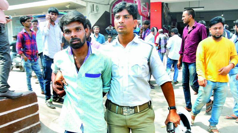 A cop arrests a person for selling tickets in black at one of the theaters at RTC crossroads during the Baahubali-2 release on Friday. (Photo: DC)