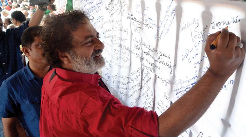 Actor-director Joy Mathew signs on a Save Munnar canvas put up by Yuvakala Sahithi in front of the  secretariat in Thiruvananthapuram on Friday. (Photo: Peethambaran Payyeri)