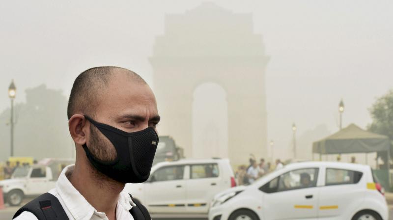 A man takes protection against pollution as smog covers India Gate in New Delhi. (Photo: PTI)