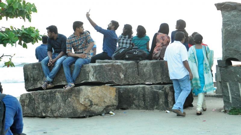 Youngsters take selfie sitting atop a sculpture at beach in Kozhikode on Friday. 	 	Venugopal