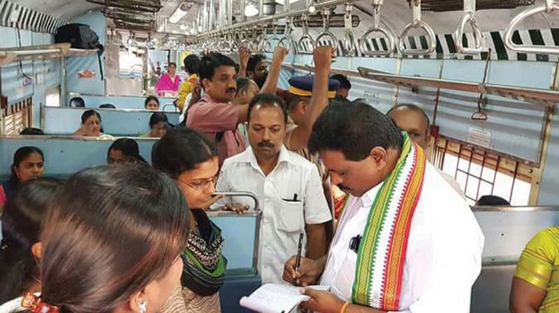 Kodikkunnil Ramesh, MP, notes down complaints from passengers while on board MEMU train