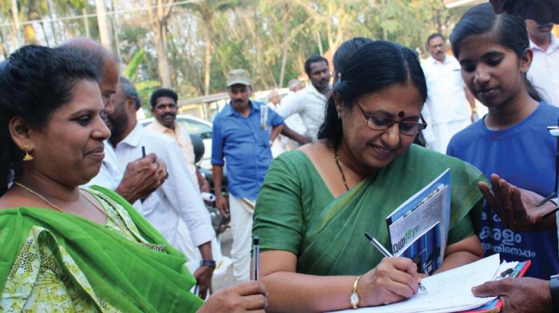T.N. Seema signs a document during the function to announce Thuruthikkara as a green village.