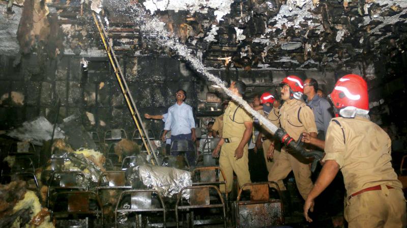 Fire force officials double-check burnt ceiling to ensure that the fire doesnt re-emerge from them at Padmanabha Theatre near East Fort on Thursday morning. 	(Photo: G.G. Abhijith)