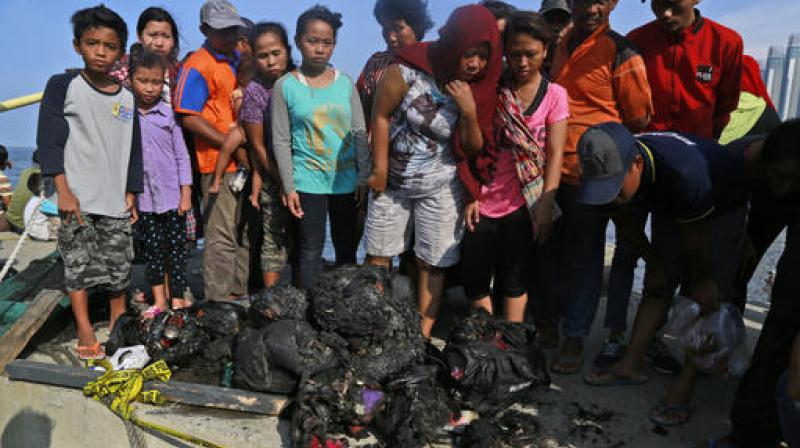 People inspect charred personal belongings of the passengers of a ferry that caught fire off the coast of Jakarta, at Muara Angke Port in Jakarta, Indonesia. (Photo: AP)