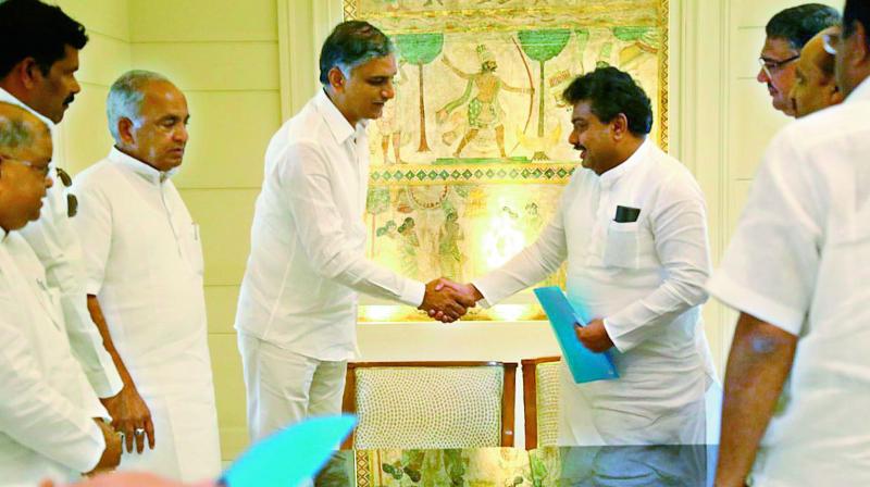 Telangana and Karnataka ministers T. Harish Rao and M.B. Patil exchange files after their meeting in Hyderabad on Thursday. (Photo: DC)
