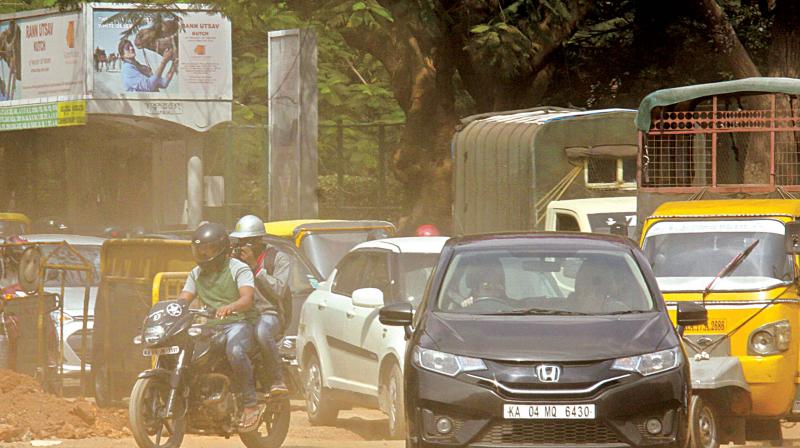 People go through a tough time due to dust pollution at Mahatma Gandhi Circle, in Bengaluru on Thursday. (Photo: DC)
