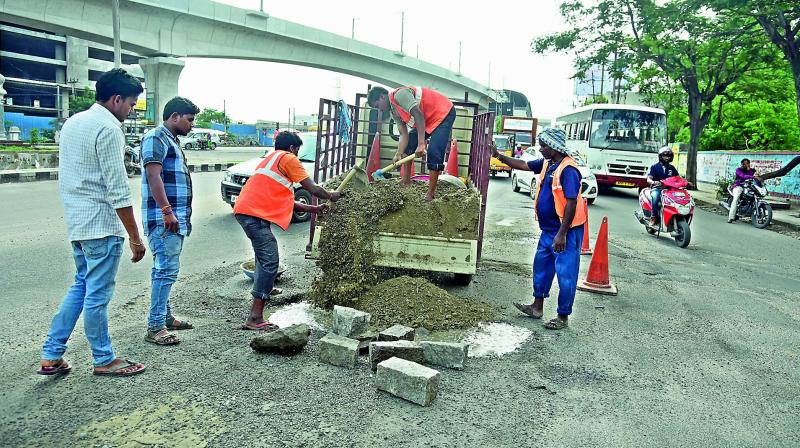 GHMC workers are filling up potholes with bitumen at Moosapet Y junction in Hyderabad on Tuesday. (Photo: DC)