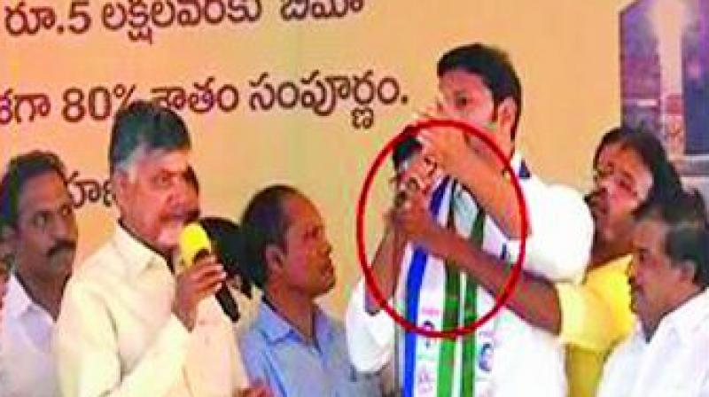 A TV grab shows a Telugu Desam activist grabbing the mike of YSR Congress MP Avinash Reddy who was praising YSR during a meet addressed by Chief Minister N. Chandrababu Naidu.