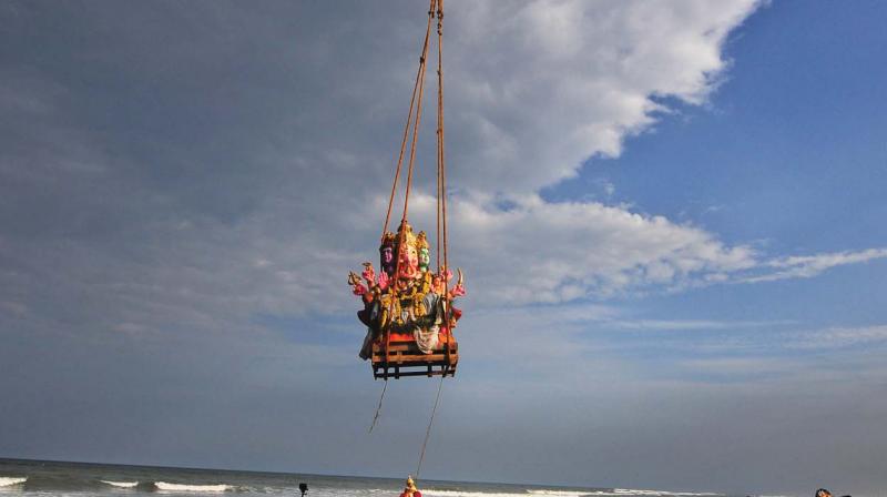 Crowds watch a JCB immerse a huge Ganesha idol in the sea near Pattinapakkam on Thursday (Photo: DC)