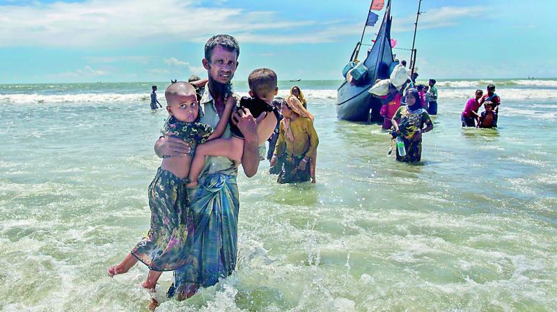 A Rohingya Muslim man walks to the shore carrying two children after they arrived on a boat from Myanmar to Bangladesh in Shah Porir Dwip, Bangladesh on Thursday. Nearly three weeks into a mass exodus of Rohingya fleeing violence in Myanmar, thousands are still flooding across the border in search of help in Bangladesh. (Photo: AP)