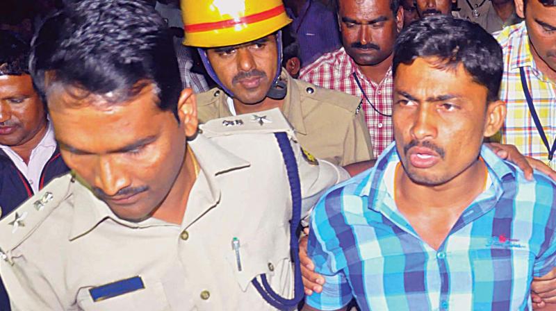 Sugarcane farmer Chandru who attempted suicide by climbing atop a mobile tower in Belagavi, being led away by the police