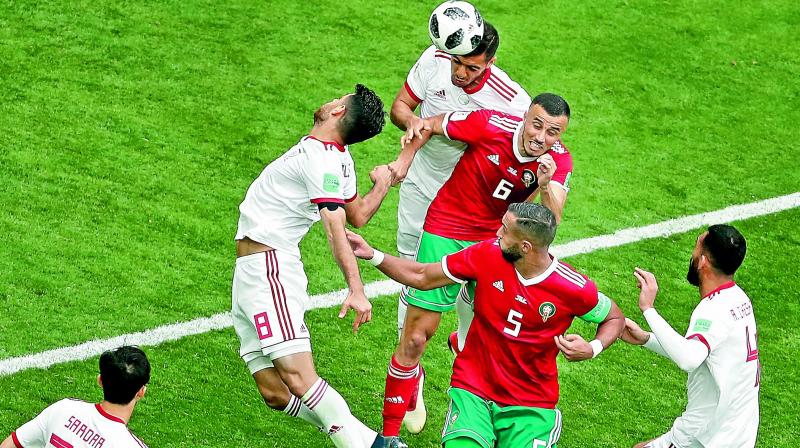 Romain Saiss (centre) of Morocco goes for a header during their Group B match against Iran at the St Petersburg Stadium on Friday.	(Photo:AP)