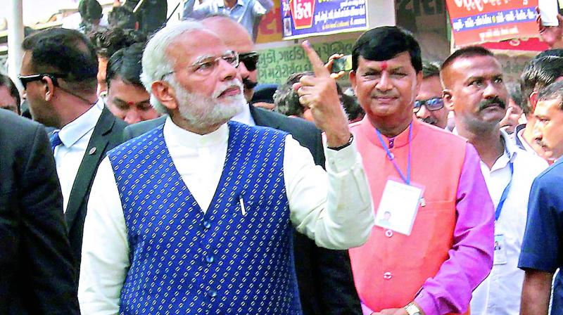 Prime Minister Narendra Modi shows his finger marked with indelible ink after casting his vote in the second phase of the Assembly elections in Ahmedabad on Thursday. The Congress immediately called it a road show and violation of the EC code. (Photo: PTI)