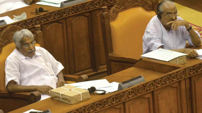 Former chief minister Oommen Chandy with solar report on his table in the Assembly on Thursday.  KC(M) leader K.M. Mani, MLA, is seated next to him. (Photo: PEETHAMBARAN PAYYERI)