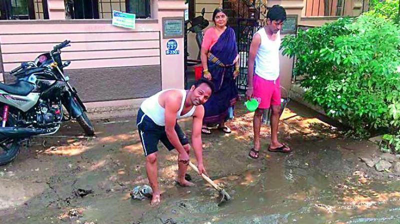 Residents of Mallikarjunanagar clear the silt which flows onto the roads when it rains.