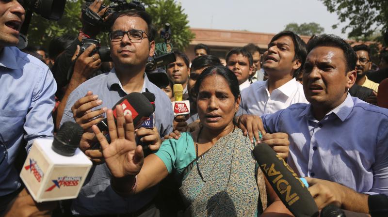 Journalists crowd around Asha Devi, mother of the victim of the fatal 2012 gangrape on a moving bus, after the Supreme Court verdict in the case. (Photo: AP)