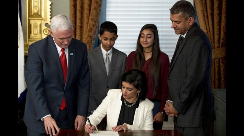 Seema Verma signs an official document while accompanied byVice President Mike Pence, husband Sanjay, her son Shaan, and her daughter Maya, during a swearing in ceremony in the Eisenhower Executive Office Building on the White House complex in Washington. (Photo: AP)