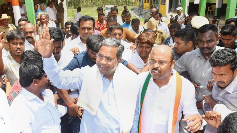 Chief Minister Siddaramaiah and his son Dr Yathindra with supporters after casting their votes at Hundi village in Mysuru on Saturday ( Image:  PTI)