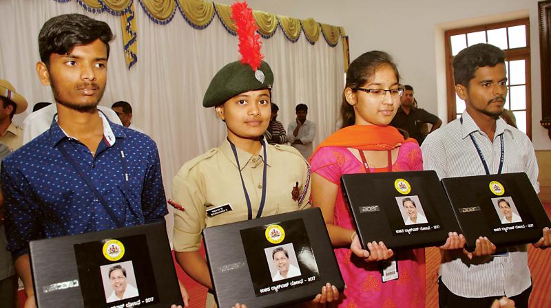 Students with the laptops distributed by the state government at Vidhana Soudha on Wednesday. (Photo: DC)