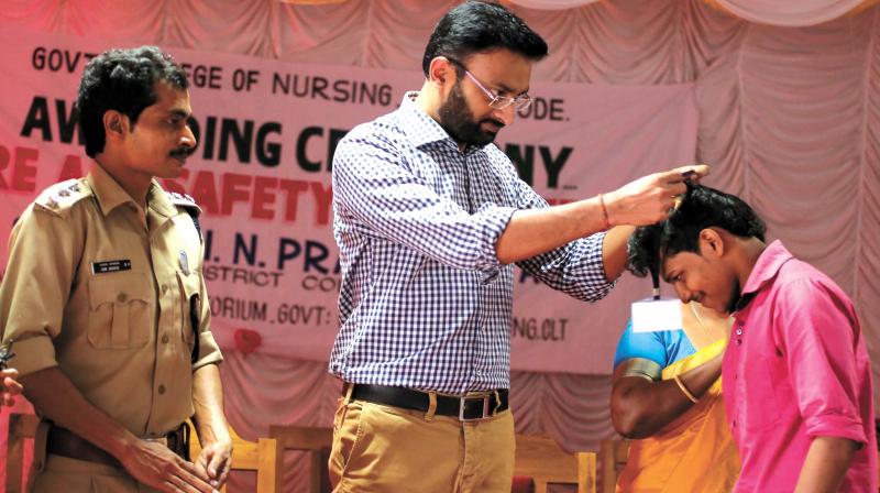 District collector N. Prasanth awards the Student Response Force badge to one of the students at the Government College of Nursing, Kozhikode, on Thursday. Also seen is Fire and Rescue assistant divisional officer Arun Bhaskar. (Photo:  DC)