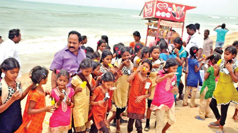 Children, belonging to tribal families in the three hills of Jarthan Kollai, Palampatti and Peenjamandai, enjoy ice-cream at the Marina beach with their host A.P Nandakumar, on Friday. (Photo:DC)