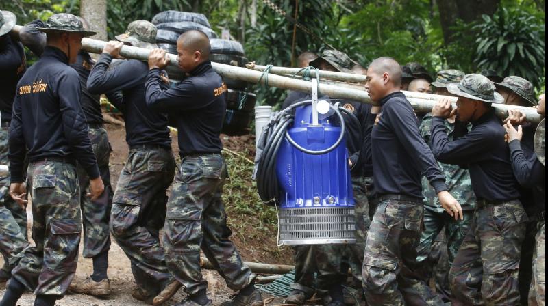 Soldiers carry a pump to help drain the rising flood water in a cave where 12 boys and their soccer coach have been trapped since June 23. Thai authorities are racing to pump out water from the flooded cave before more rains are forecast to hit the northern region. (Photo: AP)