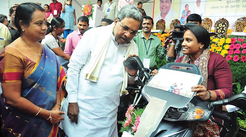 Chief Minister Siddaramaiah distributes retro-fitted two-wheelers among the physically challenged in front of Vidhana Soudha in Bengaluru on Monday (Photo: DC)