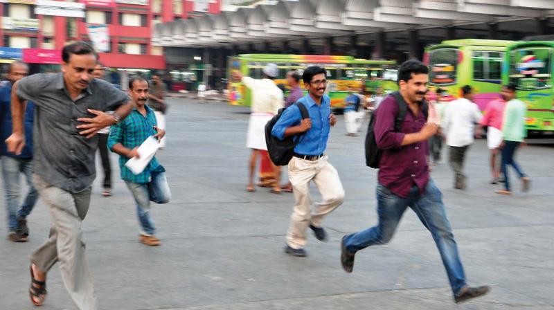 People run after a taxi at the New Bus Stand in Kozhikode on Saturday. (Photo: Venugopal)