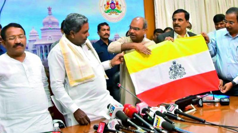 Karanata Chief Minister unveiling the yellow, white and red Karnataka flag on Thursday. 	(Photo: PTI)