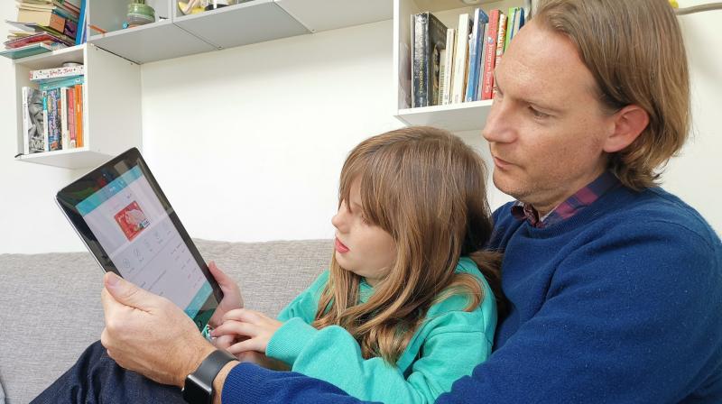 In this photo, Paddy Kelly and his daughter Ailish use Gohenry, one of a wave of digital banking apps for children, in London. (AP Photo/Kelvin Chan)