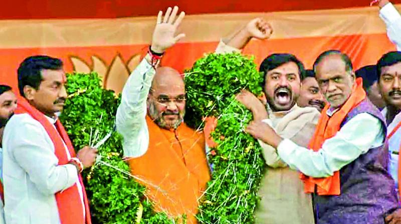 BJP president Amit Shah being garlanded by state party president (right) K. Laxman and others during an election meeting at Dubbak in Medak, on Sunday.  (PTI)